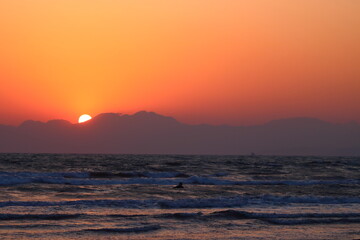 海岸線から臨む山あいに沈む夕日