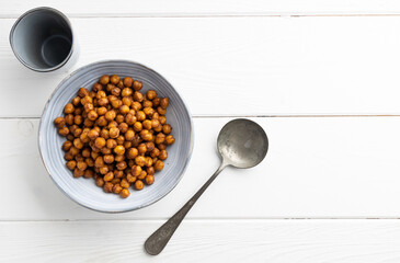 Vegan grilled chickpeas. Homemade vegan chickpeas, Crispy roasted organic chickpeas . Served as a snack in a bowl, on a wooden table top.