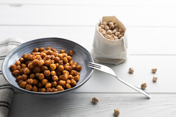 Vegan grilled chickpeas. Homemade vegan chickpeas, Crispy roasted organic chickpeas . Served as a snack in a bowl, on a wooden table top.