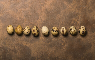 Creative quail egg layout on brown background. Quail eggs pattern. Happy easter concept. Minimal design. Copy space, flat lay, from above