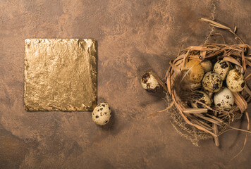 quail eggs in a nest and laid out around it border ,place for text on brown rustic background top view close up