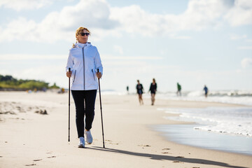 Nordic walking - middle-aged woman training on beach
