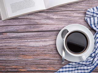 Top view of a book with a white coffee cup and a cloth placed on a wooden table. Space for text. Concept of relaxation