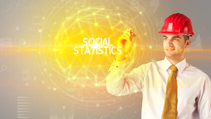 Handsome businessman with helmet drawing SOCIAL STATISTICS inscription, social construction concept