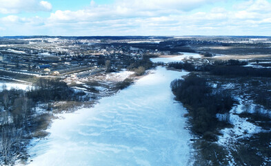Top view of frozen icy river near winter forest
