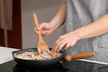 Woman cooking risotto in kitchen
