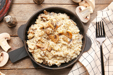 Frying pan with tasty risotto on wooden background