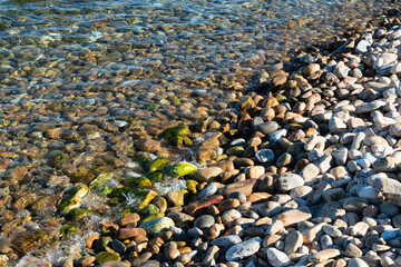 Sea coast with lots of stones at sunny day. Summer Baikal Lake landscape and pure water. Concept of relaxation, nature. Vocation time. Sea scene for card or banner.