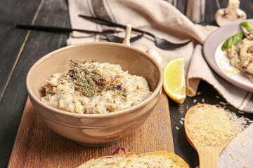 Bowl with tasty risotto on dark wooden background