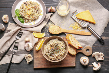 Plate and bowl with tasty risotto on dark wooden background