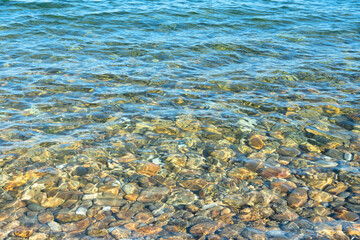 Clean water and stony bottom of the Baikal Lake at summer sunny day. Concept of relaxation, nature. Vocation time. Sea scene for card. Selective focus.