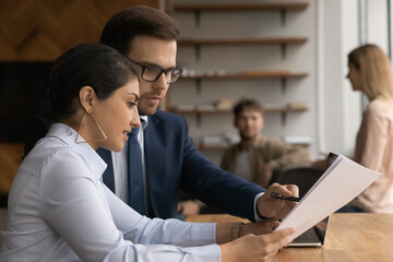 Close up diverse colleagues working together, checking documents, reading report, Indian...