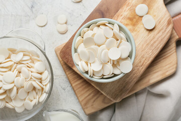 Bowls with chocolate drops on light background