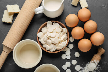 Chocolate drops and ingredients for bakery on dark background