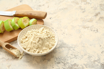 Bowl and scoop with banana flour on light background