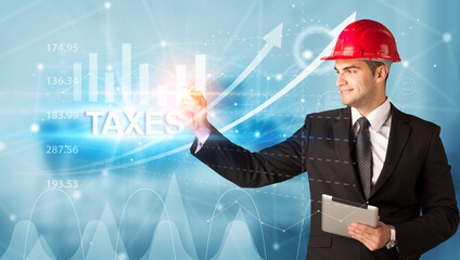 Young businessman with helmet drawing TAXES inscription, modern business technology concept