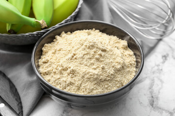 Tasty bananas and bowl with flour on light background