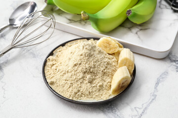 Plate with banana flour on light background