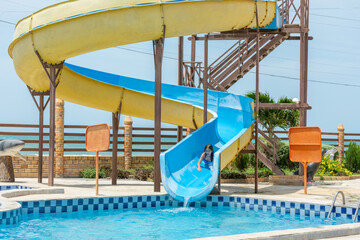 Crian&ccedil;a feliz se diverte em escorrega de &aacute;gua na piscina