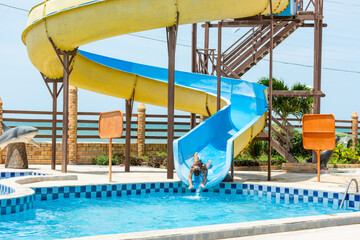 Criança feliz se diverte em escorrega de água na piscina