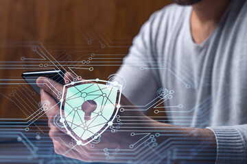 A programmer is browsing the Internet in smart phone to protect a cyber security from hacker attacks and save clients confidential data. Padlock Hologram icons over the typing hands.