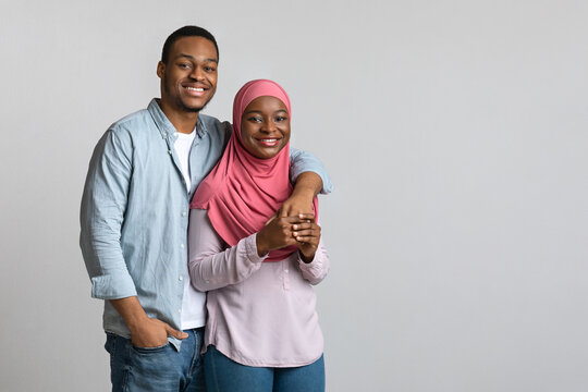 Cheerful Loving African American Muslim Couple Hugging On Grey