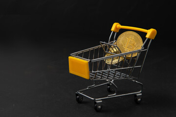 bit coin in yellow trolley on black background, electronic virtual money for web banking and international network payment,