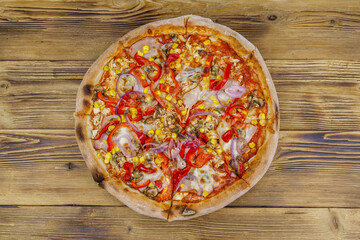 Delicious fresh pizza on a wooden table. Top view