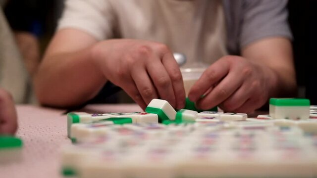 Chinese man playing mahjong with friends at home in the evening