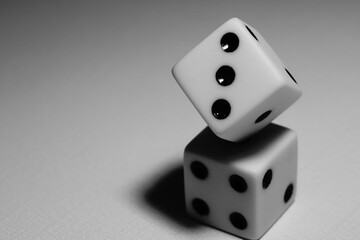Two dice balancing act. Black and white image. Concepts of life balance, harmony, and equality. Selective focus.