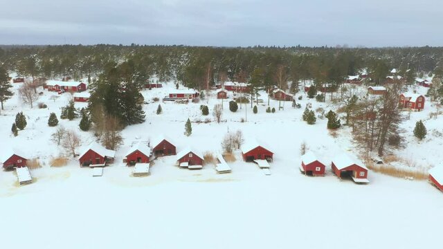 Aerial view of small coastal village covered in snow at winter. Frozen coastal landscape fishing village.