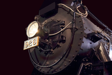 Front view of steam locomotive at night with headlight on and brass number plate nobody