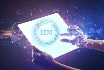 Hand holdig futuristic tablet with SEM inscription, modern technology concept