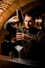 bartender accurate pours cocktail from one shaker cup to another