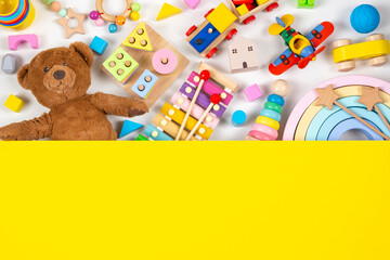 Top view to baby kids toys. Set of colorful educational wooden and fluffy toys and yellow blank background with copy space for text
