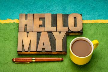 Hello May word abstract in vintage letterpress wood type with a cup of coffee against abstract paper landscape, cheerful greetings