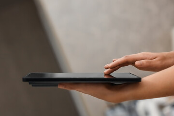 A female hand presses on the screen of a digital tablet close-up, side view. New technology concept, multimedia.