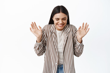 Portrait of cheerful dreamy woman close eyes and laugh, raising hands up happy, smiling with delight, standing against white background