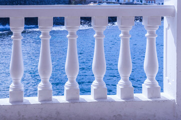 Blick durch eine Balustrade, weißes Geländer auf das in der Sonne glitzernde Meer