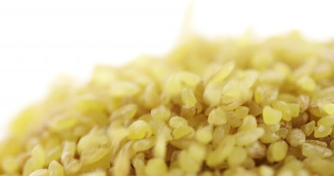 Closeup bulgur groats falling, isolated on white background. Slow motion. Food background. 