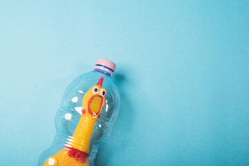 Yellow chicken in a plastic bottle on a blue background.Concept of stop plastic pollution,global warming,recycling plastic,plastic free.