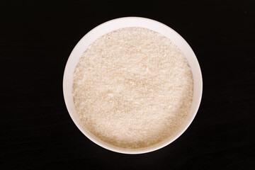 pile of Grated coconut in round white bowl on black table top view