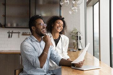 Overjoyed African American couple received amazing good news in letter, wife and husband wearing...