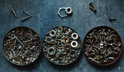 Various old nuts and screws in round tin cans, close up, stylized