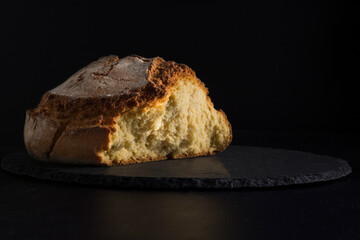 Pan artesanal de maíz abierto sobre fondo negro 