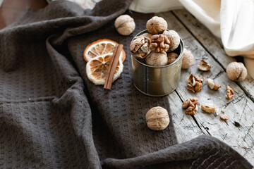 Walnuts in a tin of yellow metal next to the shell and the nuts on the inside. Decorated with dried oranges and a cinnamon stick. Composition of products and food on a wooden Board