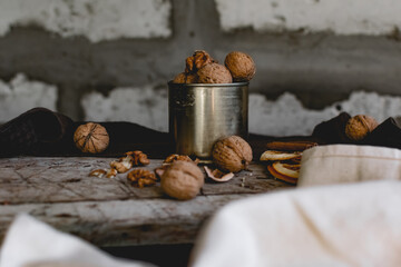 Walnuts in a tin of yellow metal next to the shell and the nuts on the inside. Decorated with dried oranges and a cinnamon stick. Composition of products and food on a wooden Board