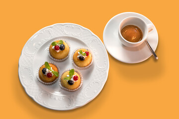 cup of espresso coffee with muffins in white plate in top view isolated on orange background