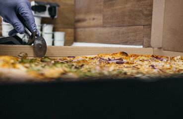 Pizza in a cardboard box with a crafting plate and pizza cutter. Bio packing for pizza