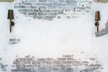 Vintage aged white brick wall with 2 retro lamps.